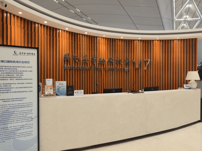 The entrance to the V7 International First Class Lounge at Nanjing Lukou International Airport features a reception desk and informational signage.