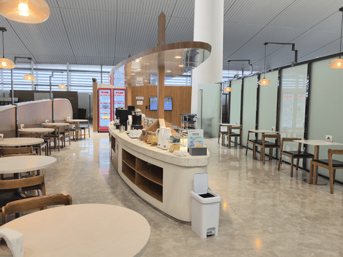 The V7 International First Class Lounge at Nanjing Lukou International Airport features a self-serve beverage station with adjacent seating areas.