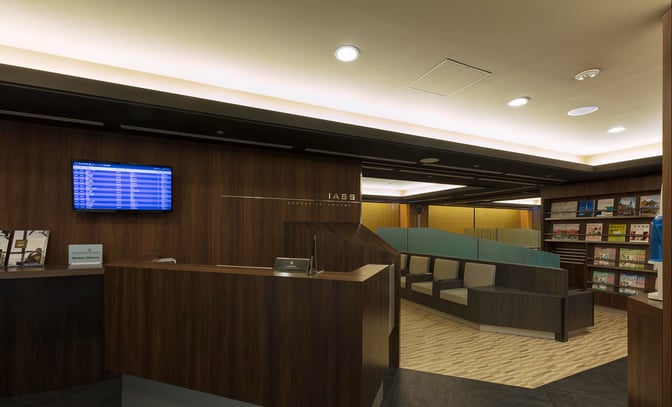 The IASS Executive Lounge at Narita International Airport features a reception desk, seating area, and a display of reading materials.