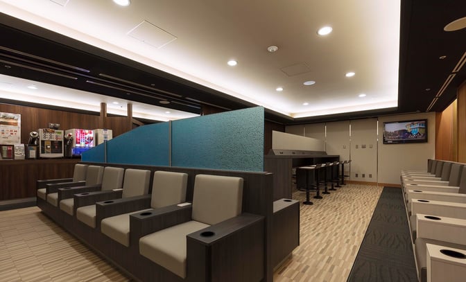 Seating in the IASS Executive Lounge 1 at Narita International Airport includes individual chairs with armrests and a nearby beverage station.