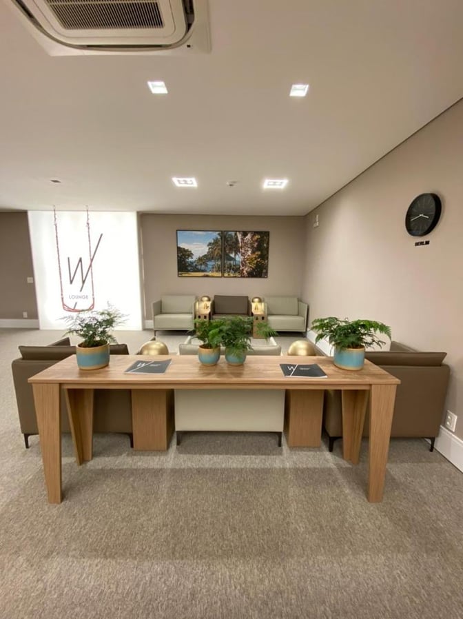 The W Lounge at Navegantes Airport features a seating area with sofas and a table adorned with potted plants.