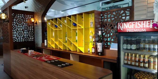 The Travel Club Annex bar at Kolkata Airport features a selection of spirits and a refrigerator stocked with various beers.