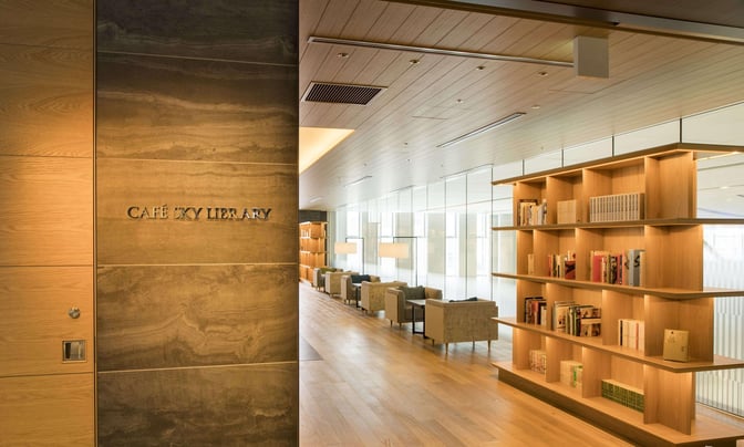 The entrance to CAFÉ SKY LIBRARY at New Chitose Airport features a wooden wall with signage and visible seating and bookshelves inside.