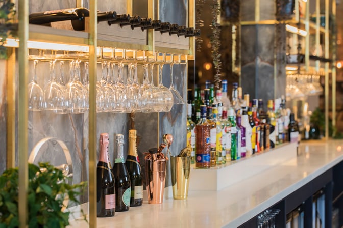 The Aspire Lounge at Newcastle Airport features a bar with a selection of wines, spirits, and hanging glassware for guests.