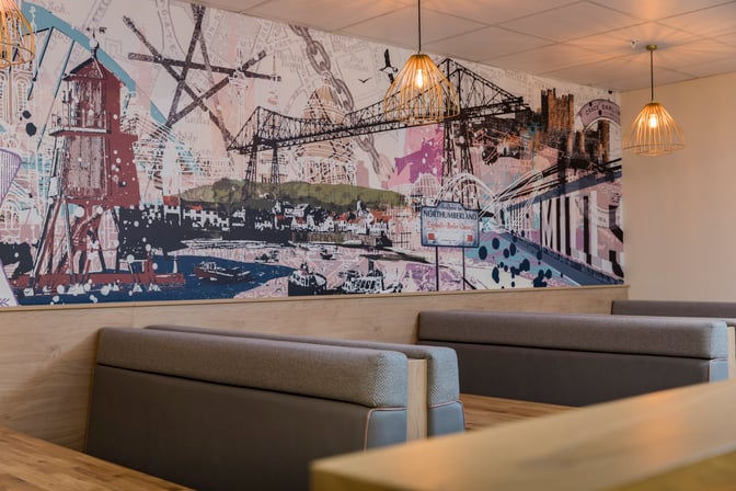 Booth seating in the Aspire Lounge at Newcastle Airport features a mural depicting local landmarks and attractions.