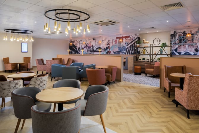 The Aspire Lounge at Newcastle Airport features a seating area with various chairs and tables, offering a comfortable space for travelers.