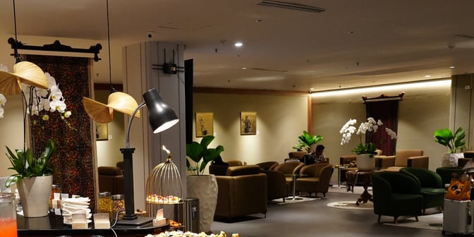 The Concordia Lounge at Ngurah Rai International Airport features a seating area with comfortable chairs and tables, surrounded by decorative plants.