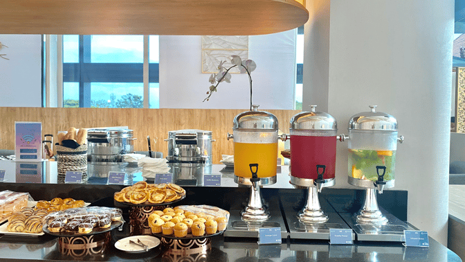 The Concordia Lounge at Ngurah Rai International Airport features a self-serve station with pastries, muffins, and beverage dispensers.