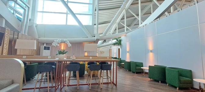 The Concordia Lounge at Ngurah Rai International Airport features a seating area with high tables, chairs, and semi-private armchairs.