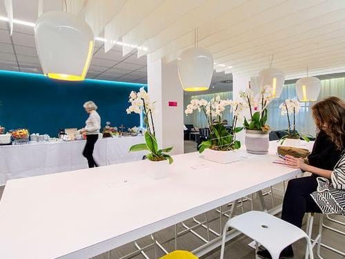 The Library Lounge at Nice International Airport features a communal table with seating and a self-serve buffet area in the background.