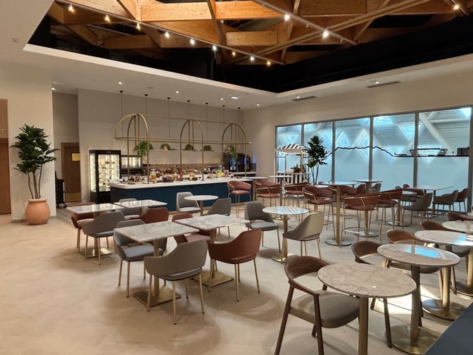 The Levity Lounge at Nice International Airport features a spacious seating area with tables and chairs near a self-serve food station.