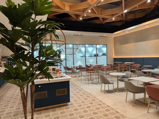 The Levity Lounge at Nice International Airport features a seating area with tables and chairs adjacent to a self-serve snack station.