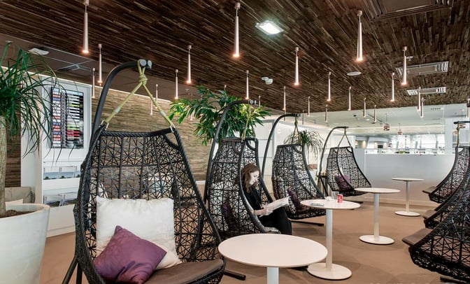 Hanging chairs and small tables in the Infinity Lounge at Nice International Airport provide a relaxed seating area for travelers.