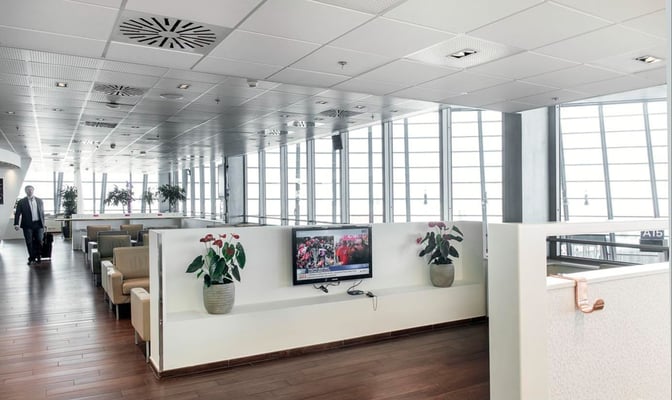 The Infinity Lounge at Nice International Airport features a seating area with armchairs, a television, and views of the tarmac.