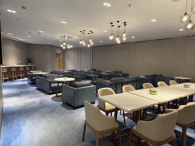 The seating area in First Class Lounge 2 at Ningbo Lishe International Airport features armchairs, tables, and a bar counter with stools.