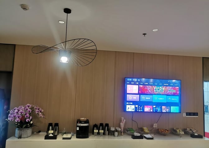The VIP Lounge at Ningbo Lishe International Airport features a refreshment area with a coffee machine, snacks, and a wall-mounted TV.
