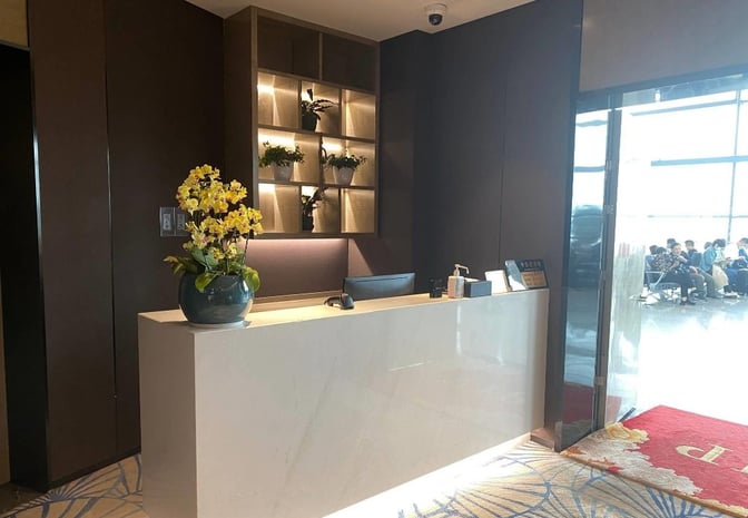 The reception area of the First Class Lounge at Ningbo Lishe International Airport features a check-in desk and decorative plants.