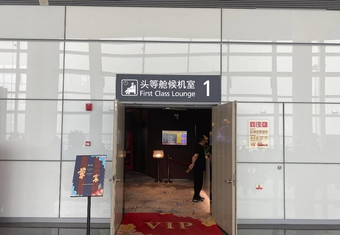 The entrance to the First Class Lounge at Ningbo Lishe International Airport features a sign and partially open doors.