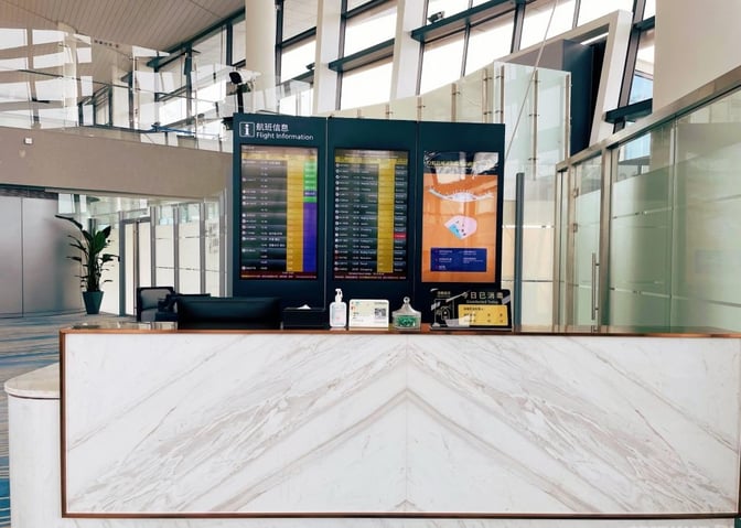 The reception desk at YONGYI VIP Room in Ningbo Lishe International Airport features flight information displays and guest check-in services.
