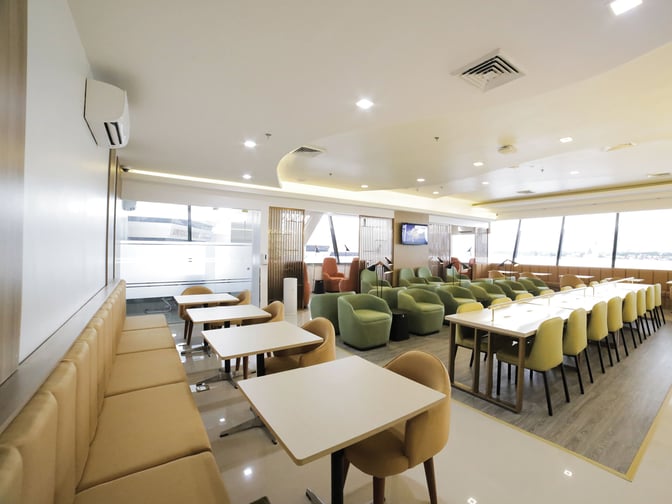 The Marhaba Lounge at Ninoy Aquino International Airport features a seating area with tables, chairs, and views of the airport.