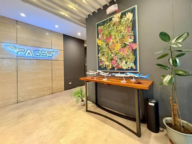 The entrance to the PAGSS Lounge at Ninoy Aquino International Airport features model airplanes on a table and a decorative wall piece.
