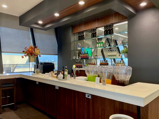 The PAGSS Lounge bar at Ninoy Aquino International Airport offers a selection of beverages with counter seating and self-serve drink dispensers.