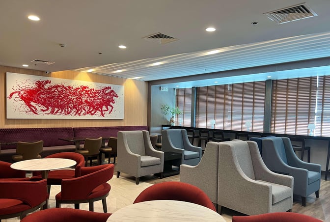 Seating area at Ninoy Aquino International Airport lounge features round tables, cushioned chairs, and a long bench with a decorative wall art.