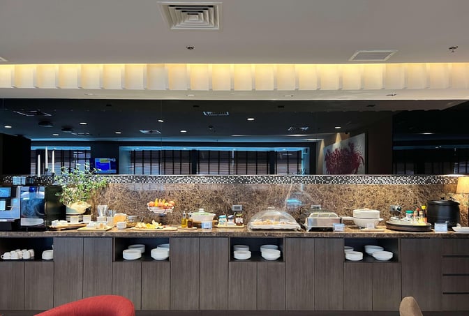 The lounge at Ninoy Aquino International Airport features a self-serve food station with various dishes, beverages, and dining essentials.