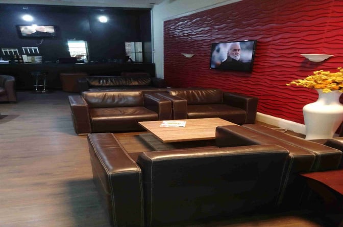 The seating area at the 9TYSIX VIP Lounge in Nnamdi Azikiwe International Airport features leather sofas and a television for entertainment.
