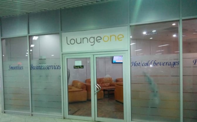 The entrance to Lounge One at Nnamdi Azikiwe International Airport features glass doors and signage for smoothies and business services.