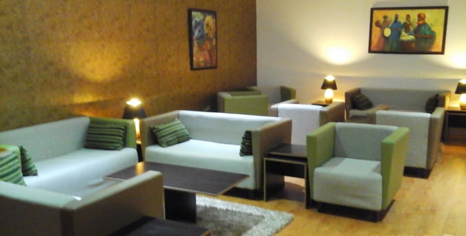 The Gabfol Lounge at Nnamdi Azikiwe International Airport features comfortable seating with sofas and armchairs, accompanied by side tables and lamps.