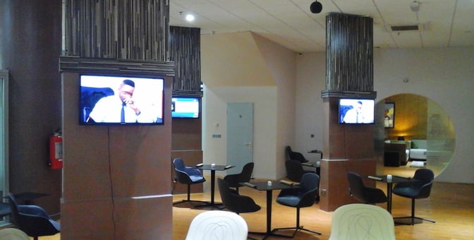 The Gabfol Lounge at Nnamdi Azikiwe International Airport features seating areas with tables and wall-mounted televisions for passenger entertainment.