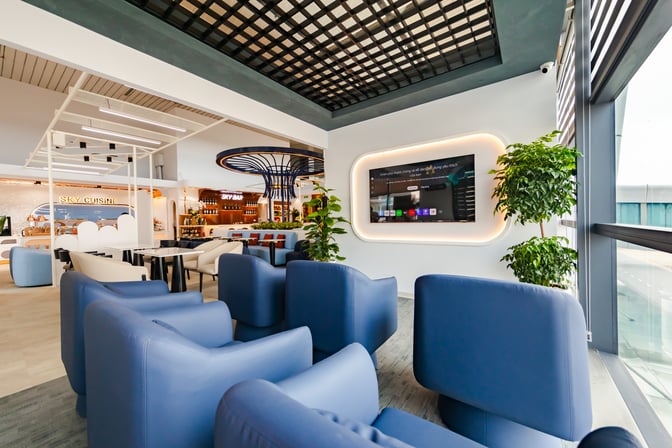 The ASG Sky Lounge at Noi Bai International Airport features a seating area with a large screen and adjacent bar and dining options.