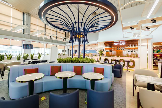 The ASG Sky Lounge at Noi Bai International Airport features a seating area with round tables and a bar offering various beverages.