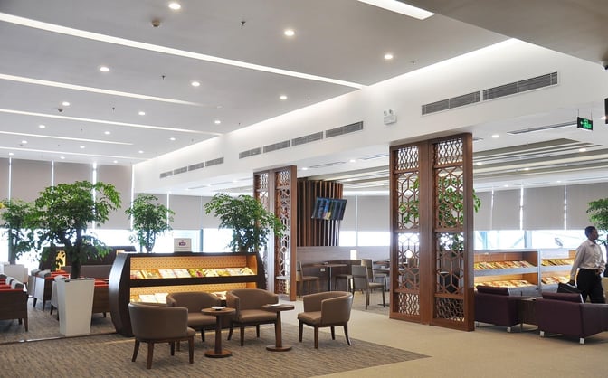 The Vietnam Airlines Lotus Lounge at Noi Bai International Airport features seating areas with tables and a magazine rack for travelers.