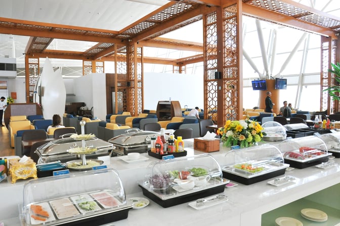 The Vietnam Airlines Lotus Lounge at Noi Bai International Airport features a self-serve food station with various covered dishes and condiments.