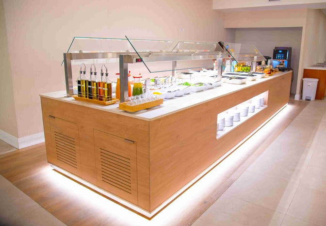 The self-serve food station at Club Kingston offers a variety of salads, dressings, and beverages for travelers.