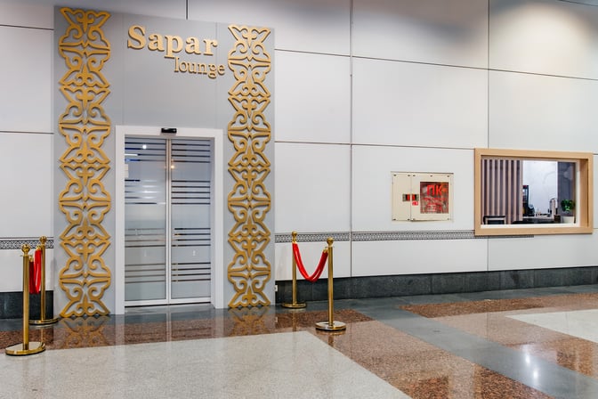 The Sapar Lounge entrance at Nursultan Nazarbayev International Airport features decorative elements and a glass door, located in the terminal area.