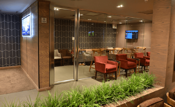 The Bidvest Premier Lounge at O. R. Tambo International Airport features a seating area with armchairs and a glass-walled meeting room.