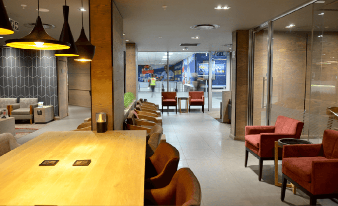 The Bidvest Premier Lounge at O. R. Tambo International Airport features a seating area with tables and chairs for travelers.