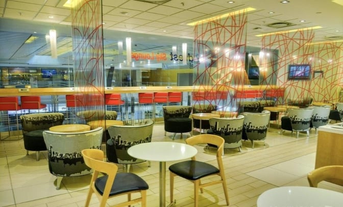 The Bidvest Sky Lounge at O. R. Tambo International Airport features seating areas with tables and chairs, offering a comfortable waiting space.