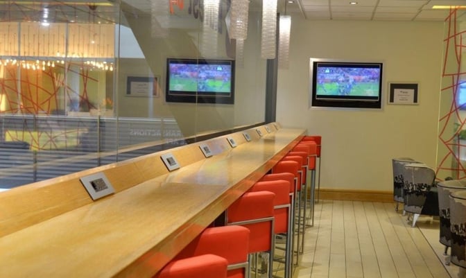 The Bidvest Sky Lounge at O. R. Tambo International Airport features a long counter with barstool seating and wall-mounted televisions.