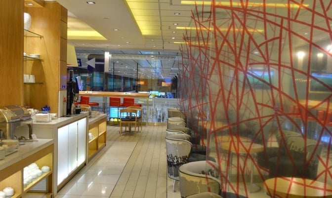 The Bidvest Sky Lounge at O. R. Tambo International Airport features a self-serve food station and seating area with tables and chairs.