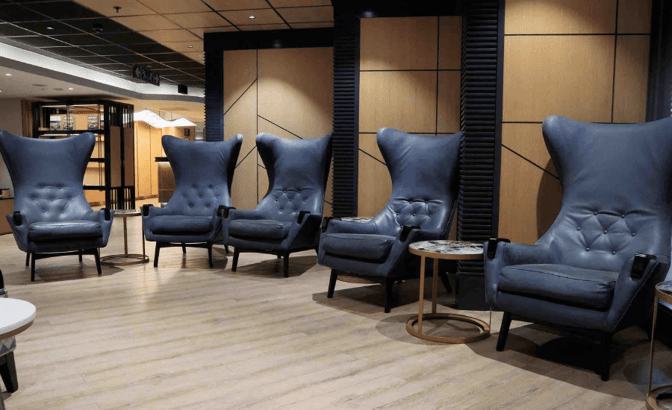 High-backed armchairs in the Bidvest Premier Lounge at O. R. Tambo International Airport offer comfortable seating with adjacent side tables.