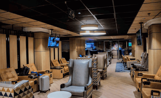 The Bidvest Premier Lounge at O. R. Tambo International Airport features comfortable seating with individual tables and mounted televisions for passenger relaxation.