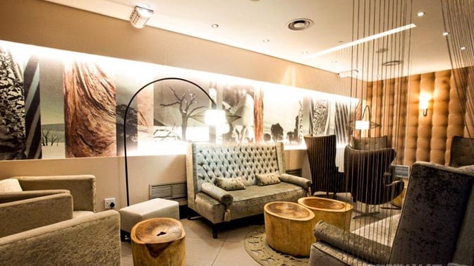 The seating area in Mashonzha Lounge at O. R. Tambo International Airport features plush chairs and sofas with decorative wall art.