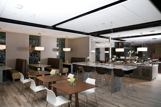 The Escape Lounge at Oakland International Airport features booth seating and a central dining area with a self-serve food station.