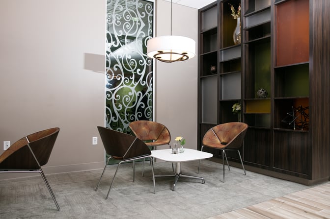 The seating area in the Escape Lounge at Oakland International Airport features modern chairs around a low table with decorative shelving.