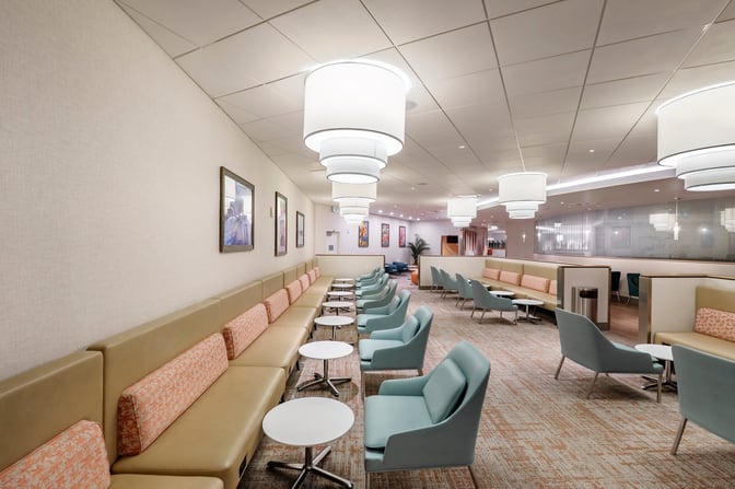 The Club MCO Airside 4 lounge features a seating area with cushioned chairs and tables, providing a comfortable space for travelers.