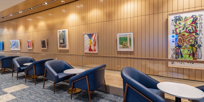 The seating area at Plaza Premium Lounge, Orlando International Airport, features comfortable chairs and small tables, with artwork displayed on the wall.
